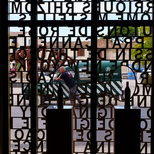 Un homme pousse une camionnette de démonstration de la maison Noilly Prat photographié au travers de la devanture du magasin. - France  - collection de photos clin d'oeil, catégorie clindoeil